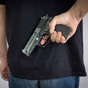 Man hiding a handgun behind his back, representing Texas gun law.