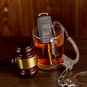 Gavel, handcuffs, and keys in a drink, representing a DWI arrest.