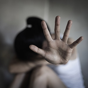 Person's hand in front of a blurry background, representing child abuse.