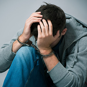 Young person in handcuffs with their head in their hands - Drug Possession Charge Limit Your Child’s Future