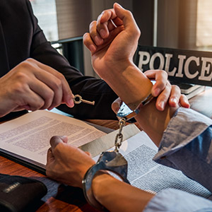 Juvenile in handcuffs talking with a probation officer. Title: Juvenile Probation Violation.
