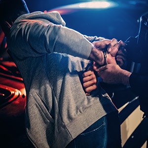 Juvenile offender being handcuffed by a police officer title "Protecting The Future Of Juveniles Accused Of Crimes."