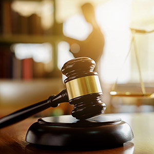 Gavel on a desk with a law student and books in the background. protecting your freedom.