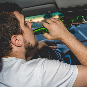 Man drinking beer while driving; risk of DWI conviction in Texas.