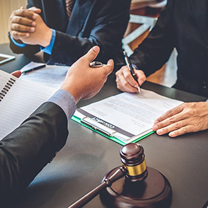 Legal consultation with attorney and client reviewing documents over a table with a gavel, regarding Collin County Criminal Defense.